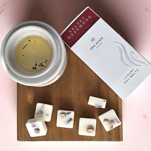 Soy wax melts with a container and packaging on a wooden board